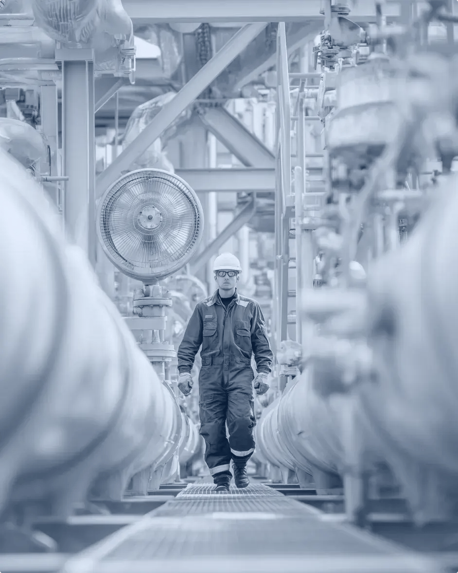 un employé marche entre deux tuyaux sur un site de production