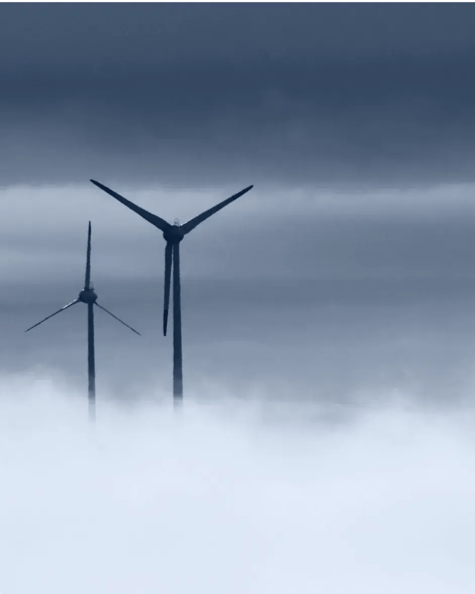 le haut d'une éolienne qui émerge des nuages