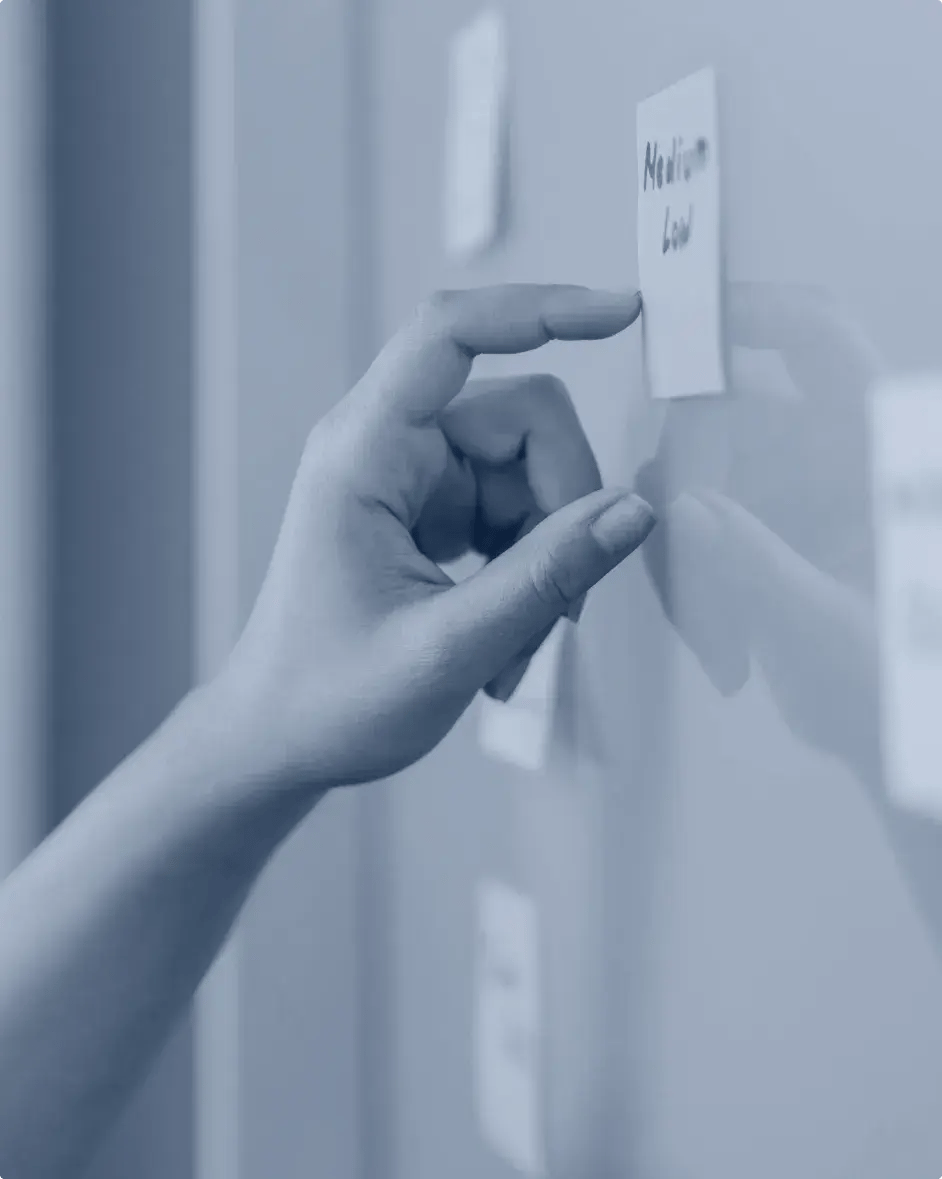 une main qui pose un post-it sur un tableau blanc