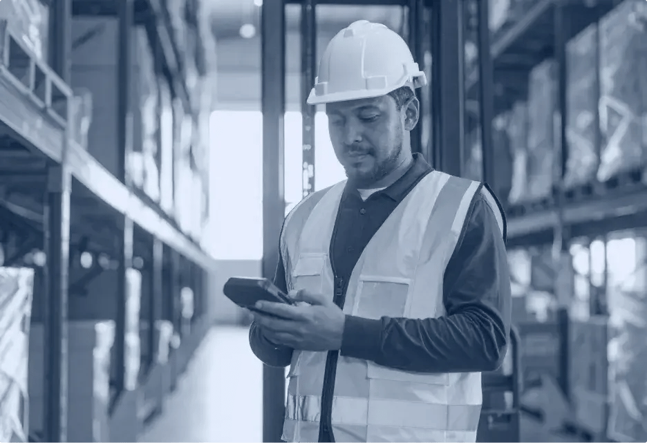 un cariste dans un entrepôt qui consulte son terminal mobile