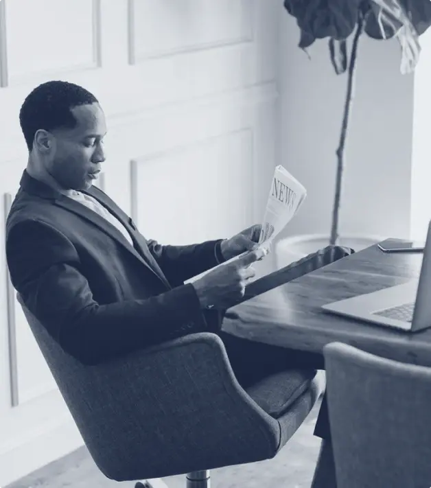 Photographie d'une personne dans un bureau lisant un journal